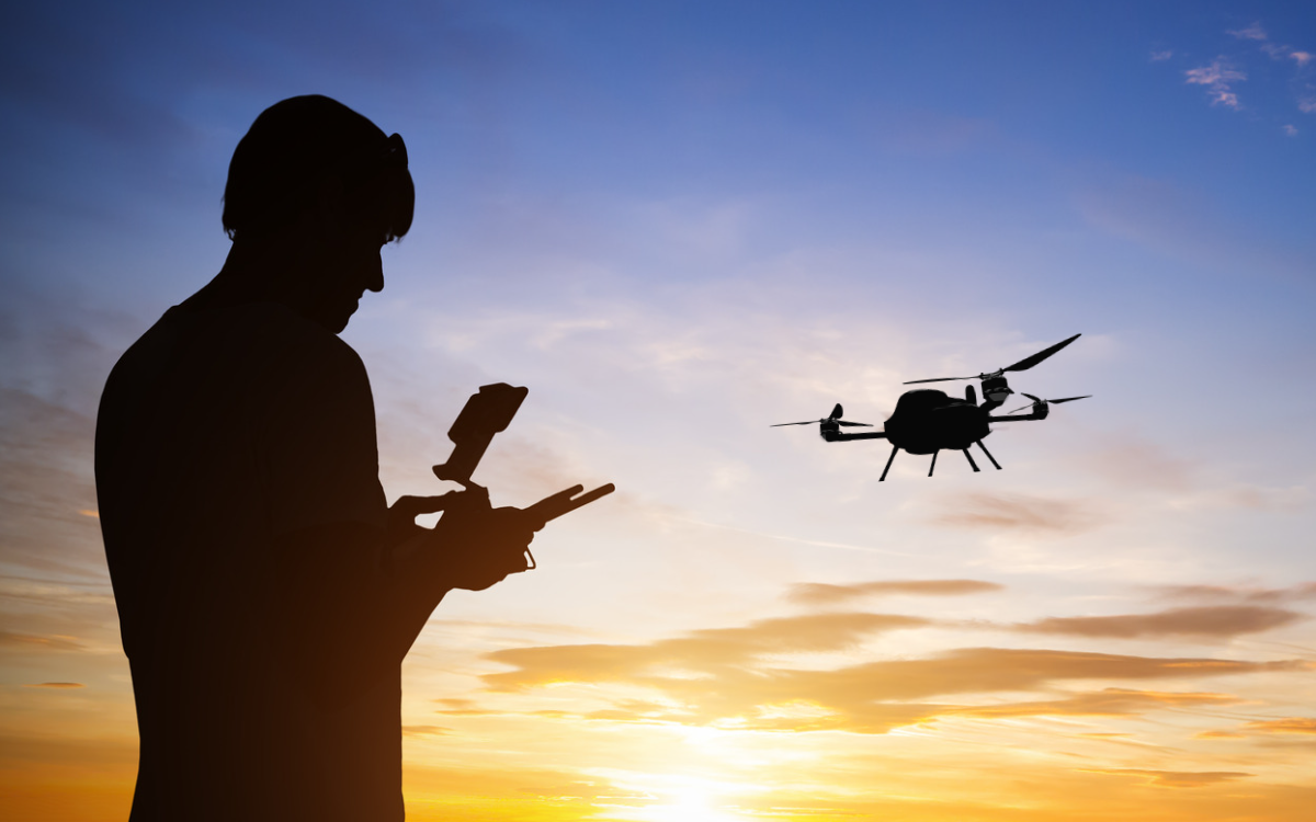 Man controlling a drone for land surveying at sunset