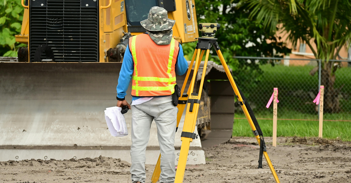 a professional land surveyor standing aside a total station